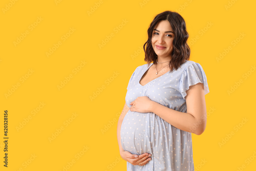 Young pregnant woman on yellow background