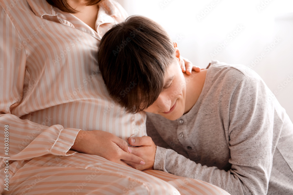 Young pregnant couple sitting in bedroom, closeup