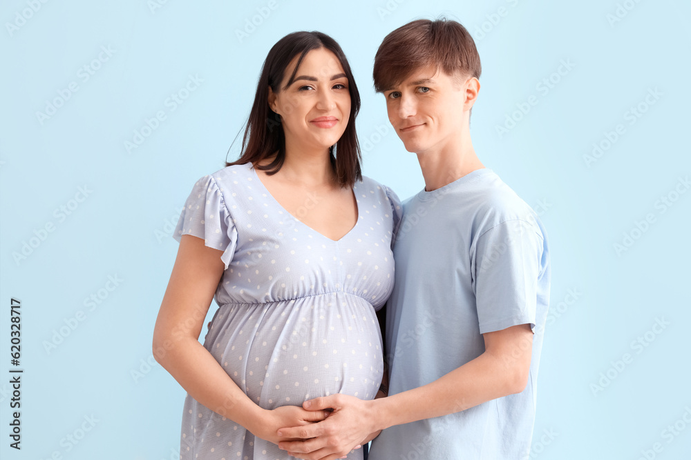 Young pregnant couple on blue background