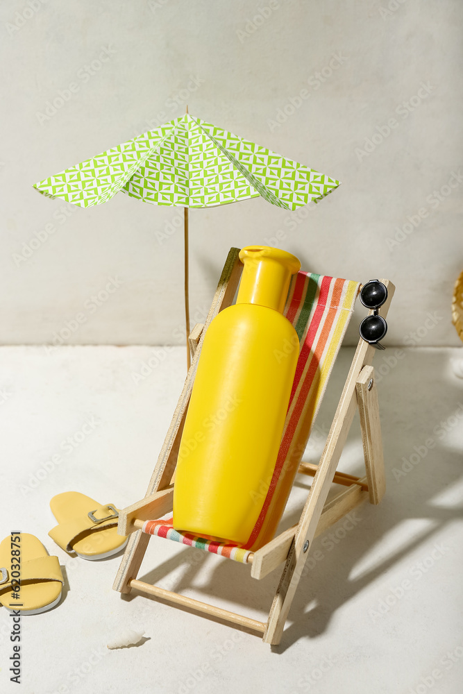 Creative composition with beach accessories and sunscreen on white table near wall