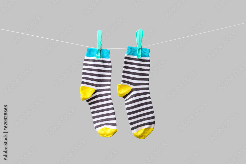 Pair of cotton socks hanging on rope against grey background