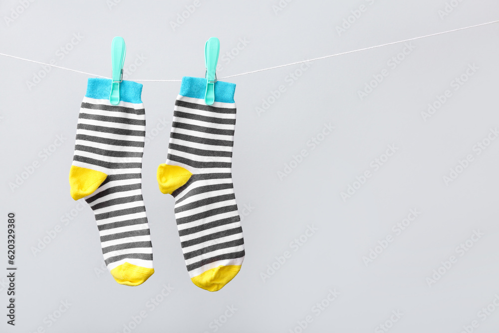 Pair of cotton socks hanging on rope against grey background