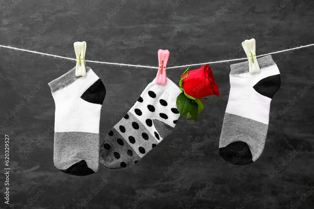 Cotton socks with rose flower hanging on rope against dark background