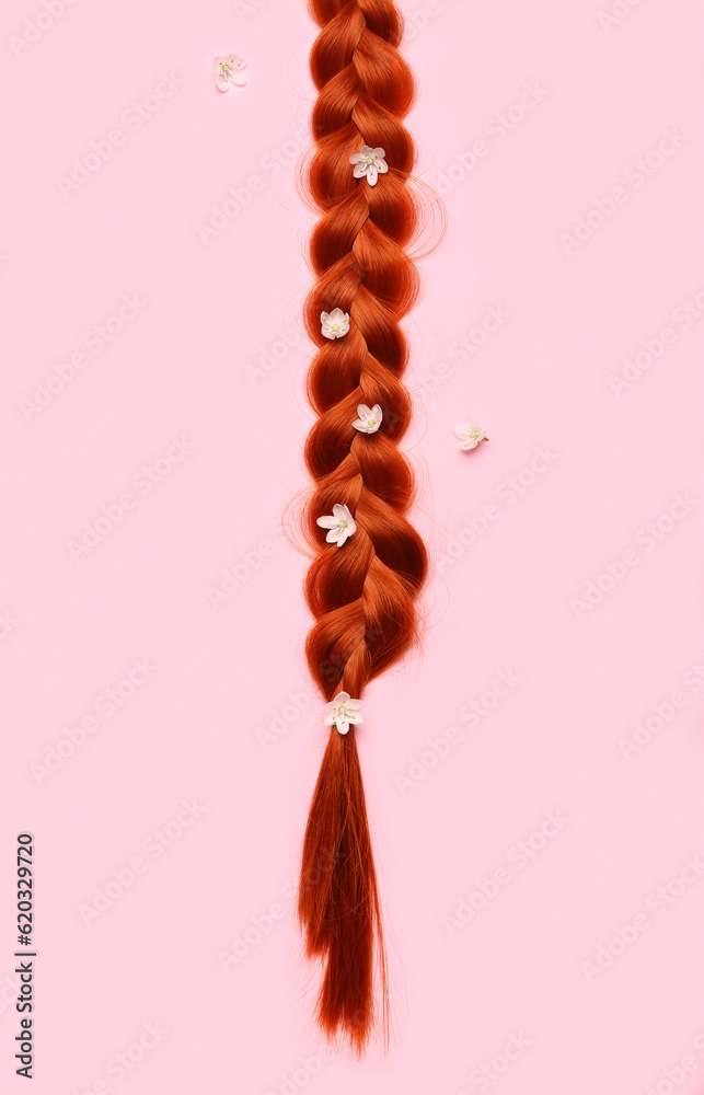 Braided ginger hair with flowers on color background, closeup