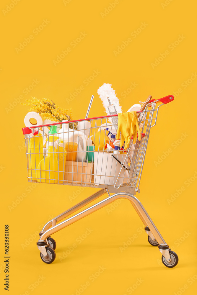 Shopping cart full of cleaning supplies with flowers on yellow background