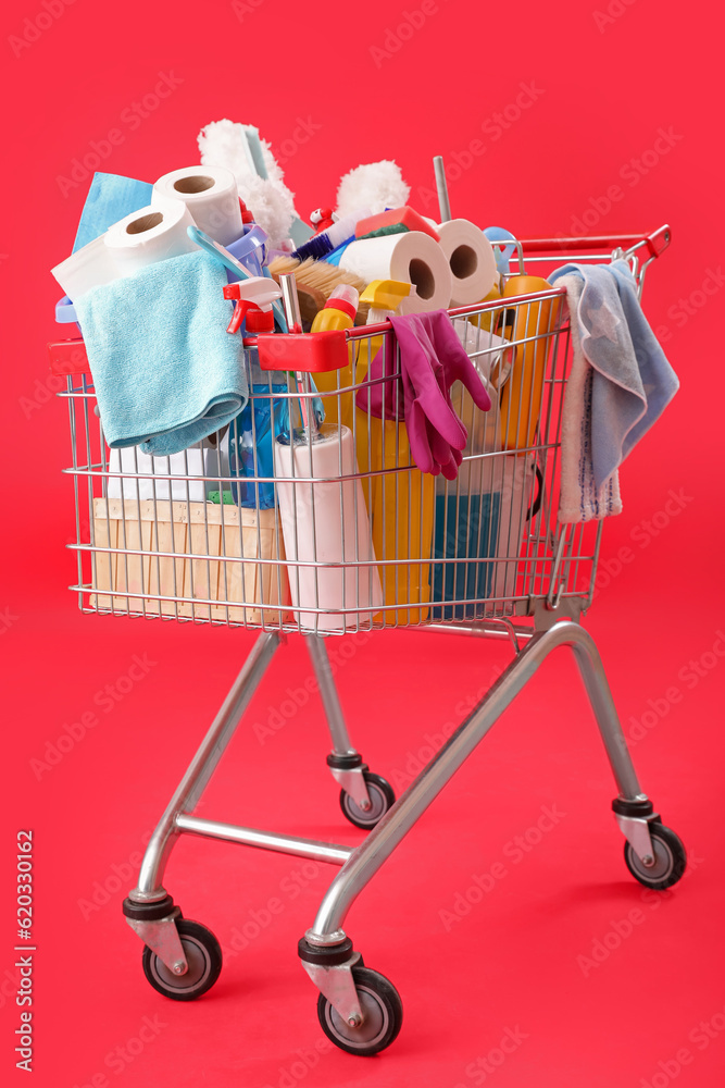 Shopping cart full of cleaning supplies on red background