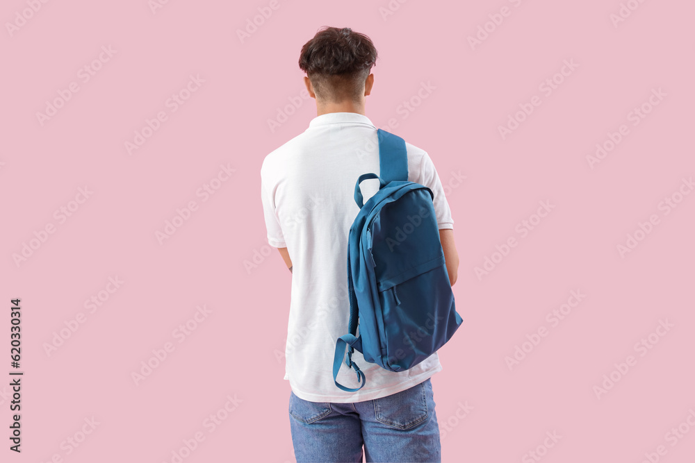 Male student with backpack on pink background, back view