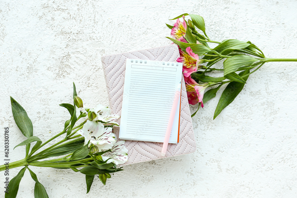 Notebooks, pen and beautiful alstroemeria flowers on light background