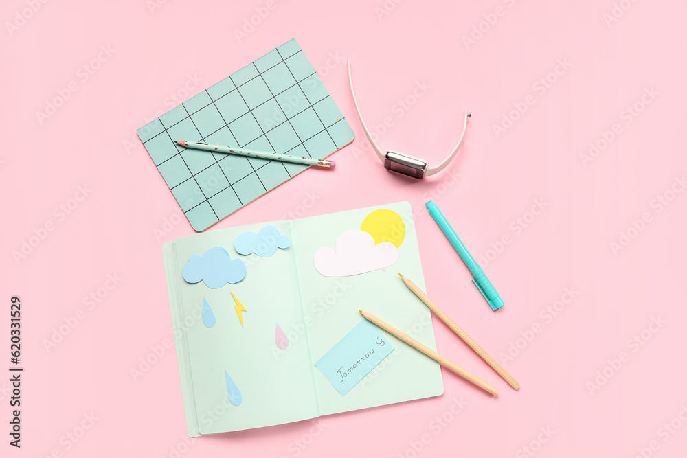 Notebooks with word TOMORROW, paper clouds, rain drops, pencils and smartwatch on pink background. W