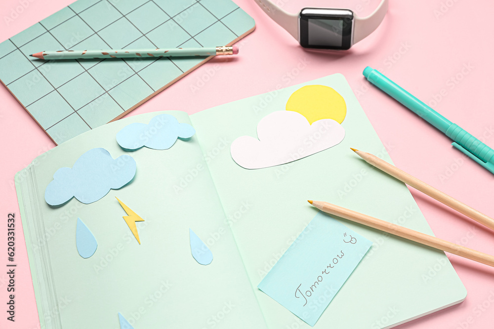 Notebooks with word TOMORROW, paper clouds, rain drops, pencils and smartwatch on pink background. W