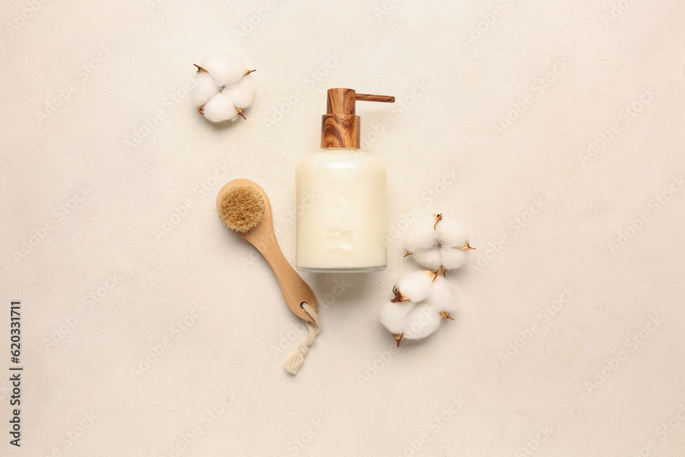 Bottle of cosmetic product, massage brush and cotton flowers on light background