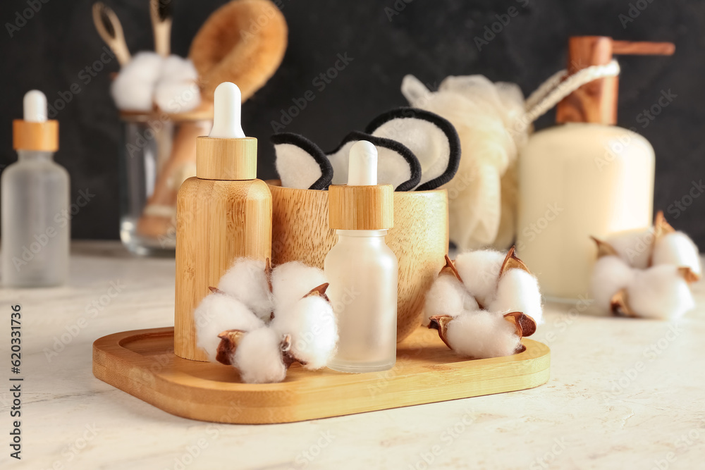 Composition with cosmetic products, bath supplies and cotton flowers on light table