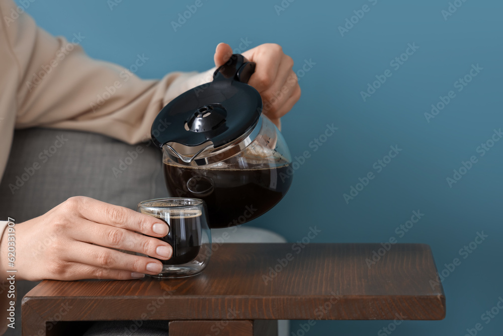 Woman pouring coffee from pot into glass on table