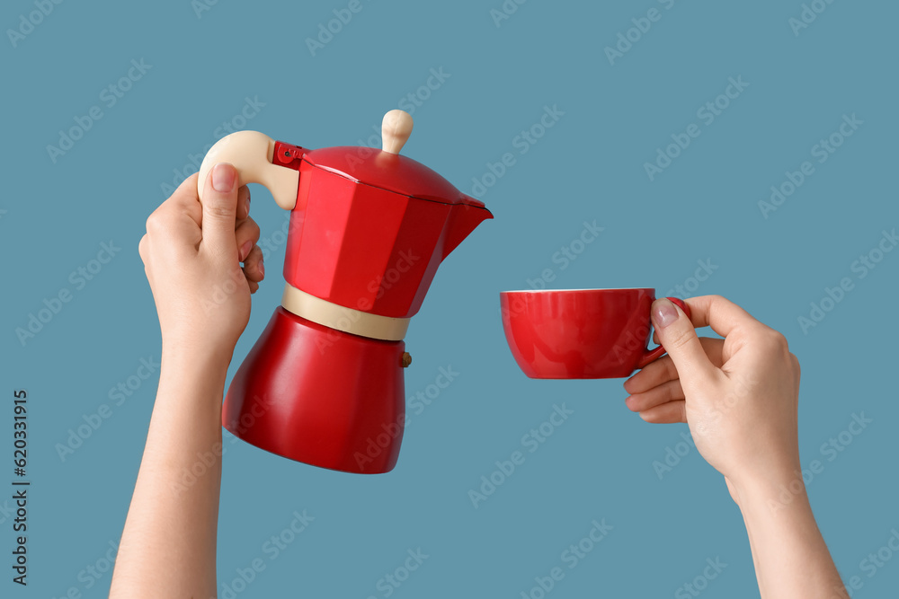 Female hands holding geyser coffee maker and cup on blue background