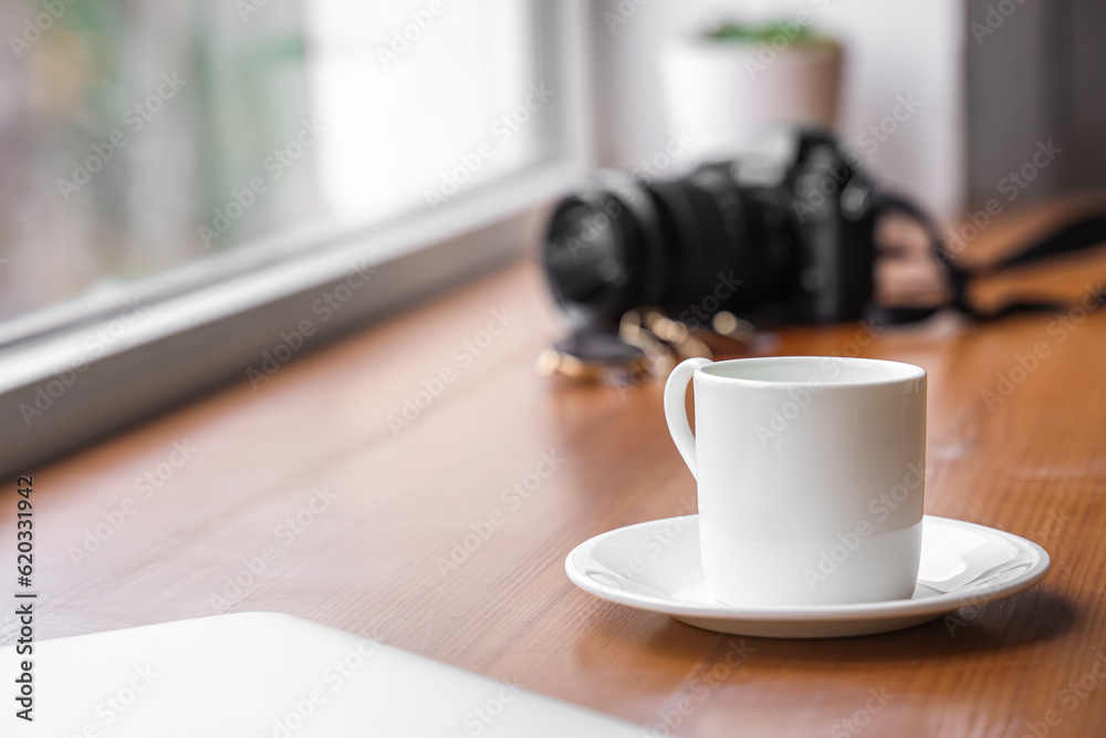 Saucer with cup of coffee on wooden windowsill, closeup