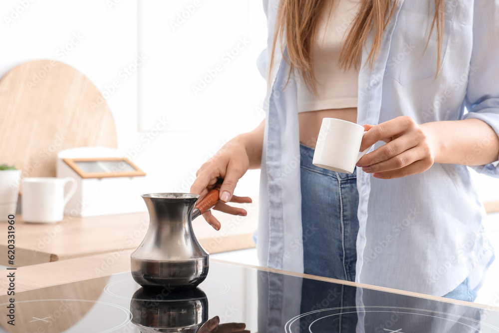 Woman brewing coffee with jezve at electric stove