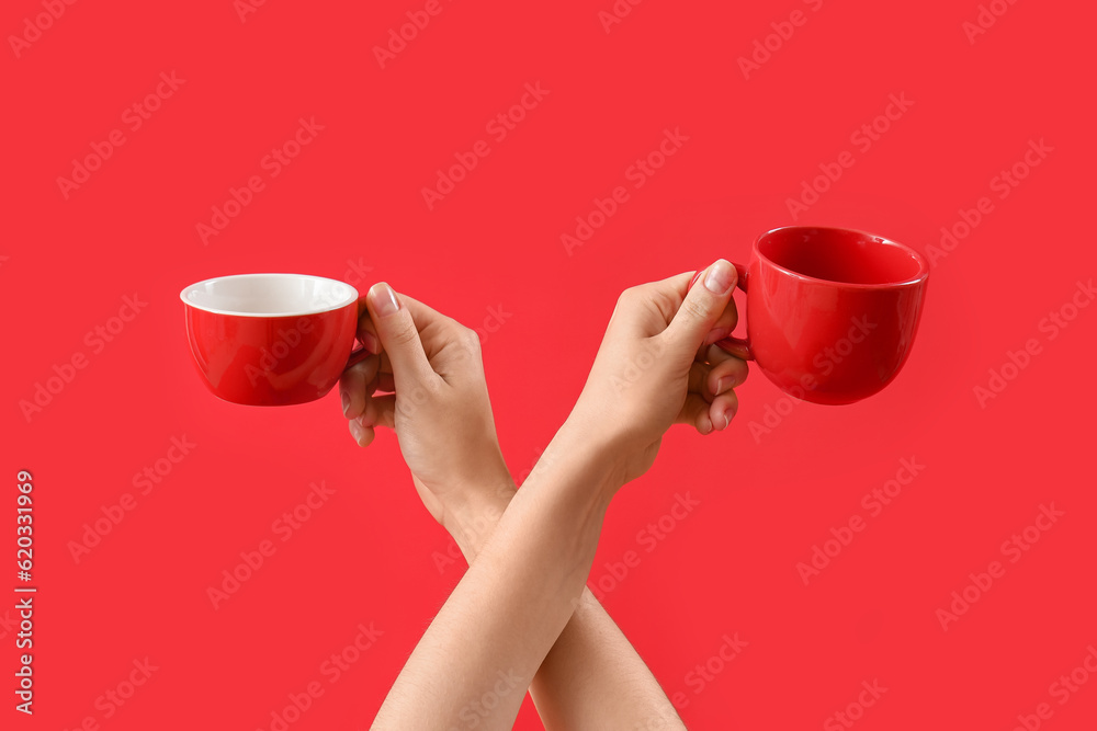 Female hands with cups on red background