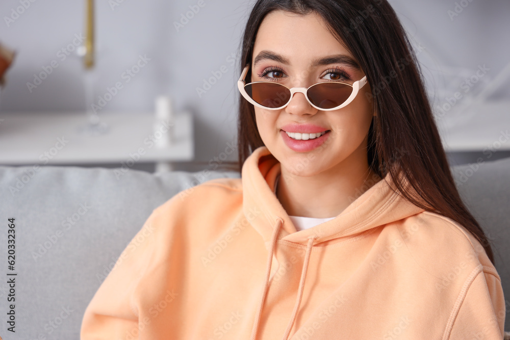 Young woman wearing stylish sunglasses at home