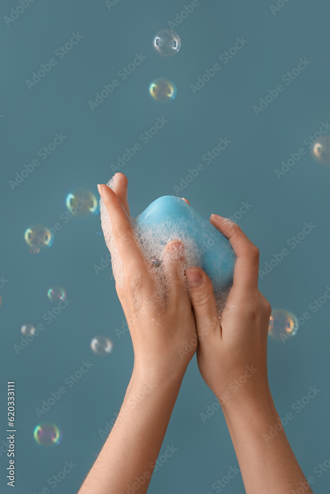 Hands with soap and bubbles on blue background