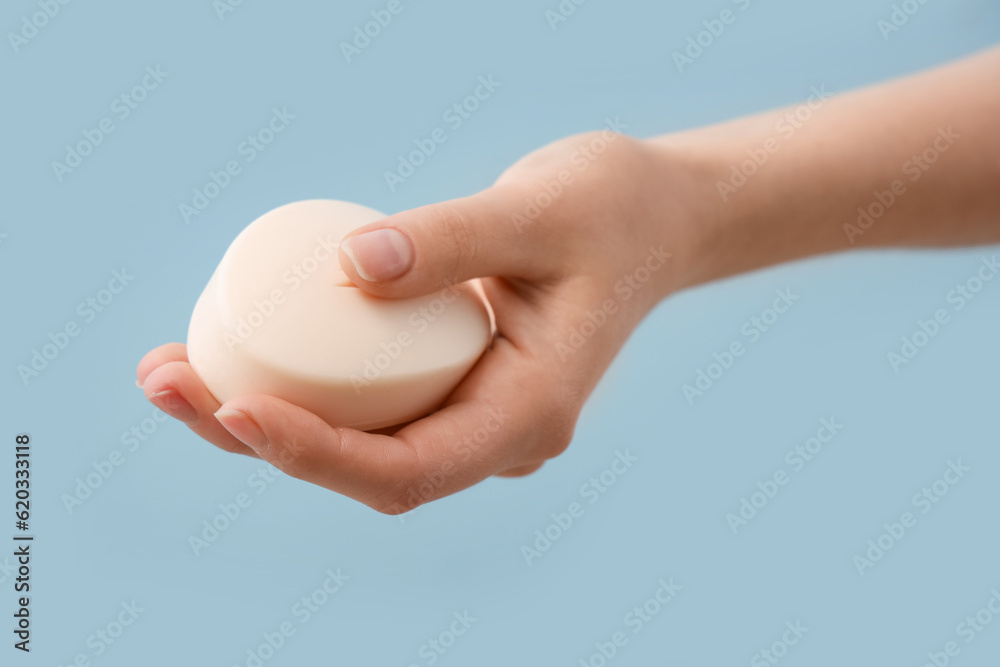 Hand with soap on light blue background