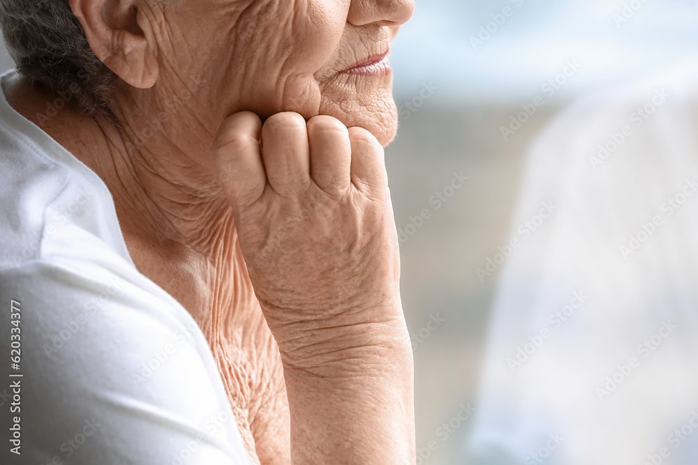 Senior woman looking in window at home, closeup