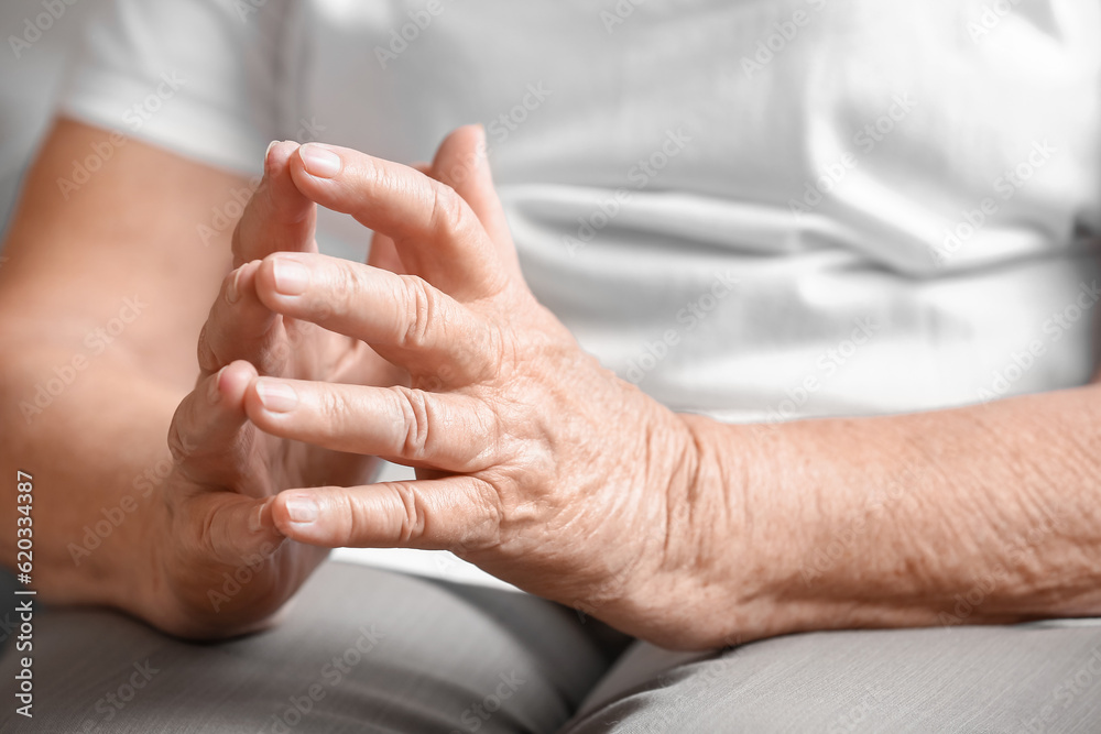 Hands of senior woman sitting at home, closeup