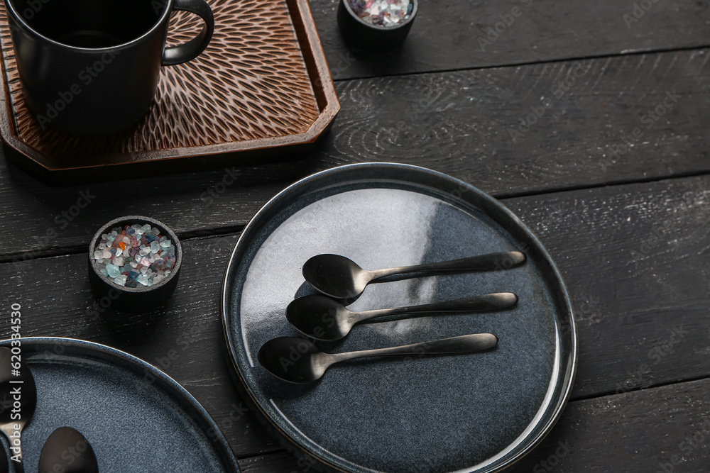 Clean plate with set of spoons on black wooden table, closeup