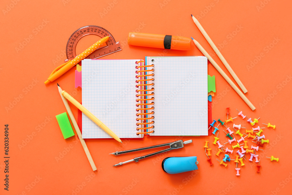 Blank notebook with different stationery on orange background