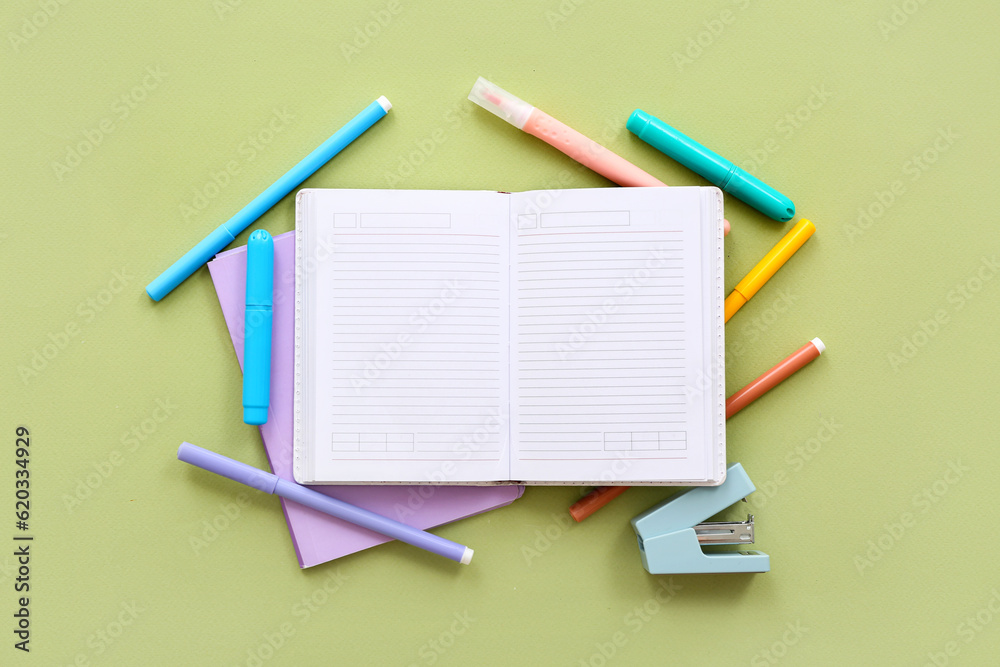 Blank notebook with different stationery on green background