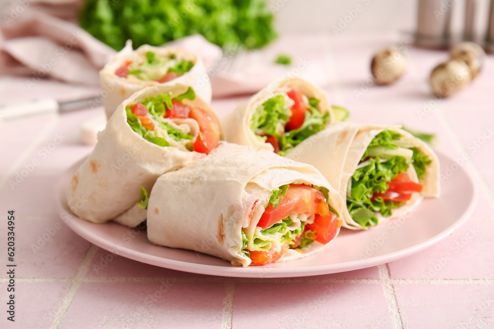 Plate of tasty lavash rolls with tomatoes and greens on pink tile background