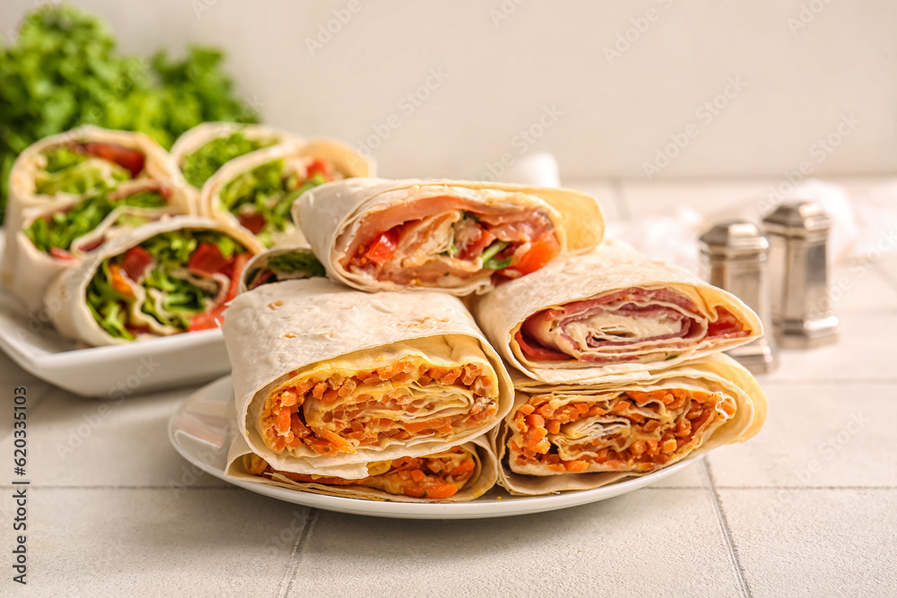 Plate of tasty lavash rolls with vegetables on table