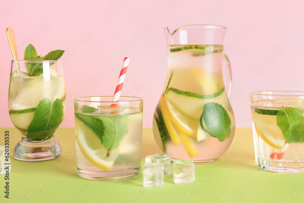 Glasses and jug of lemonade with cucumber on green table