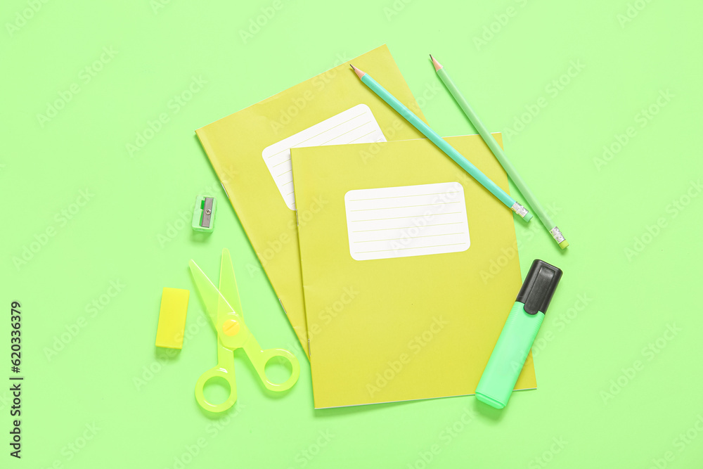 Notebooks with different stationery on green background