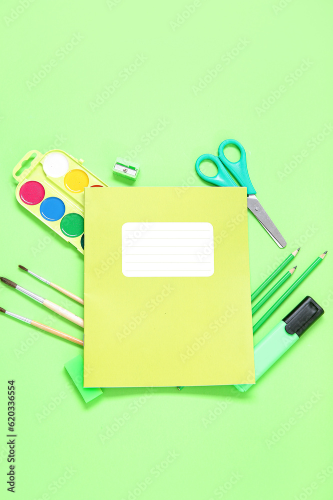 Notebook with different stationery on green background