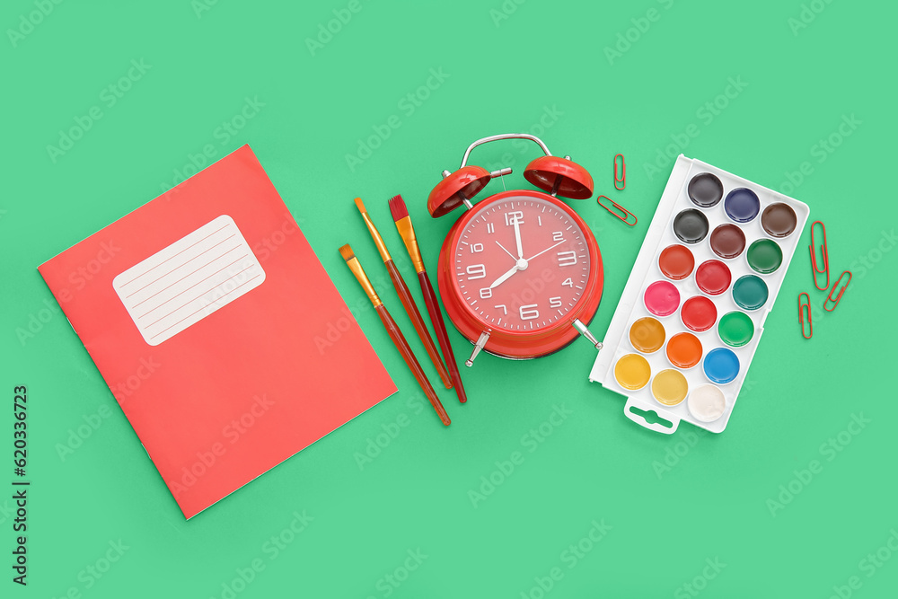 Alarm clock with different stationery on green background