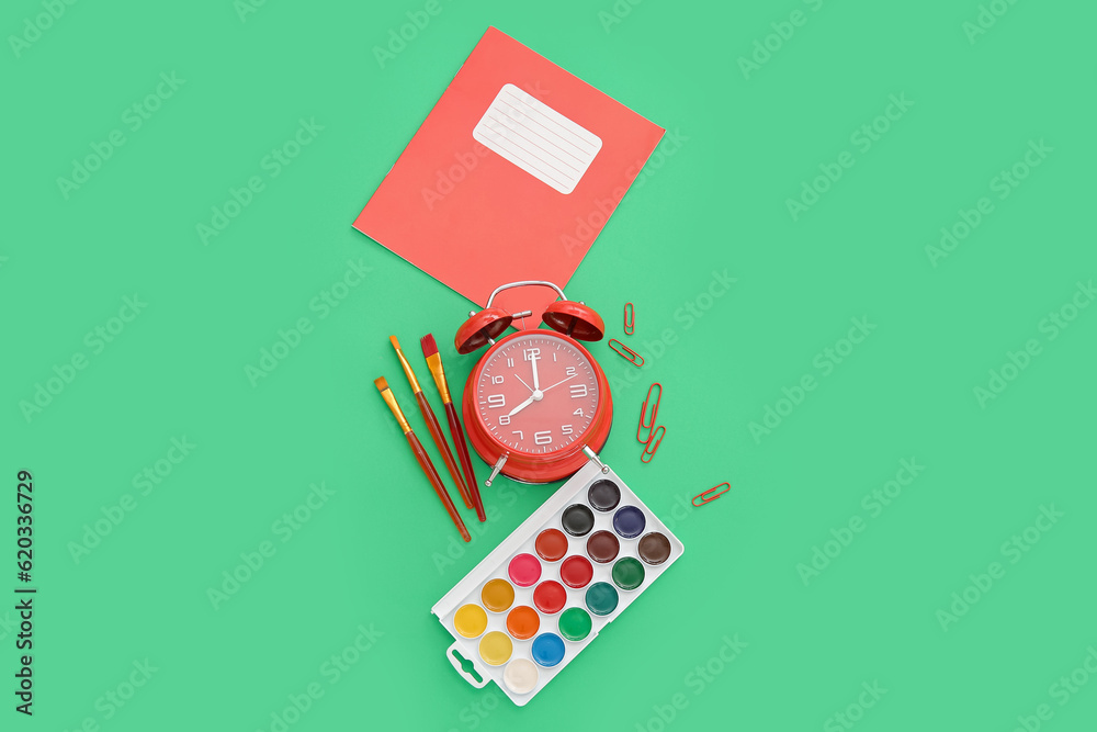 Alarm clock with different stationery on green background