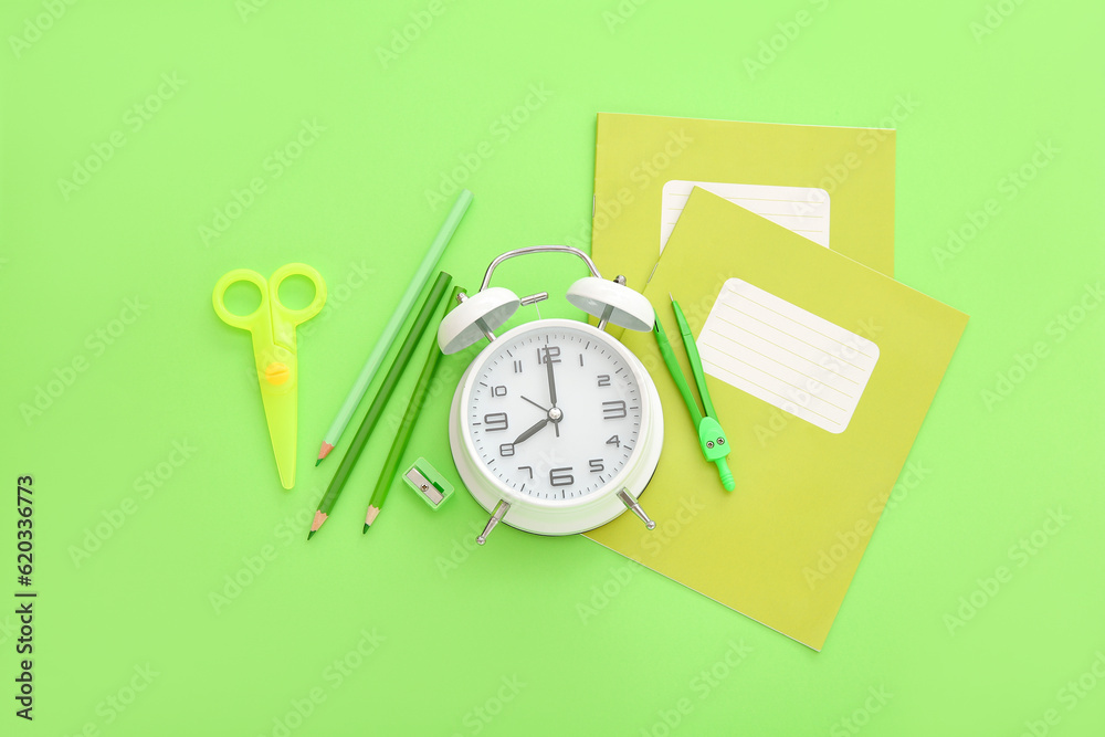 Alarm clock with different stationery on green background