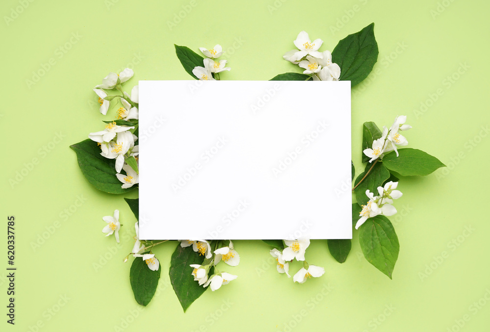 Composition with blank card and beautiful jasmine flowers on green background