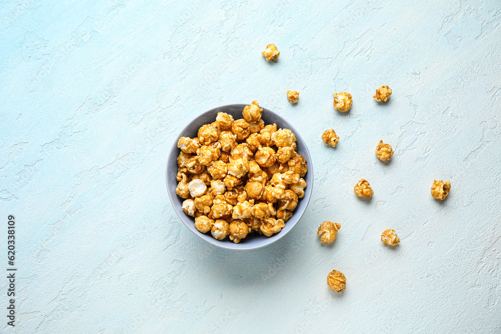 Bowl with tasty popcorn on blue background