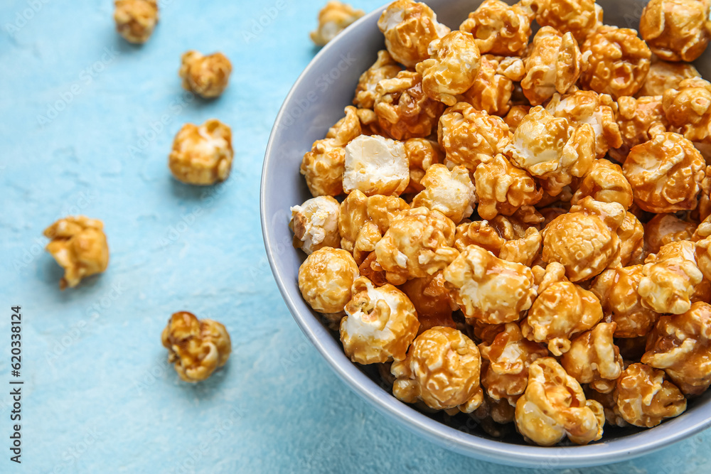 Bowl with tasty popcorn on blue background