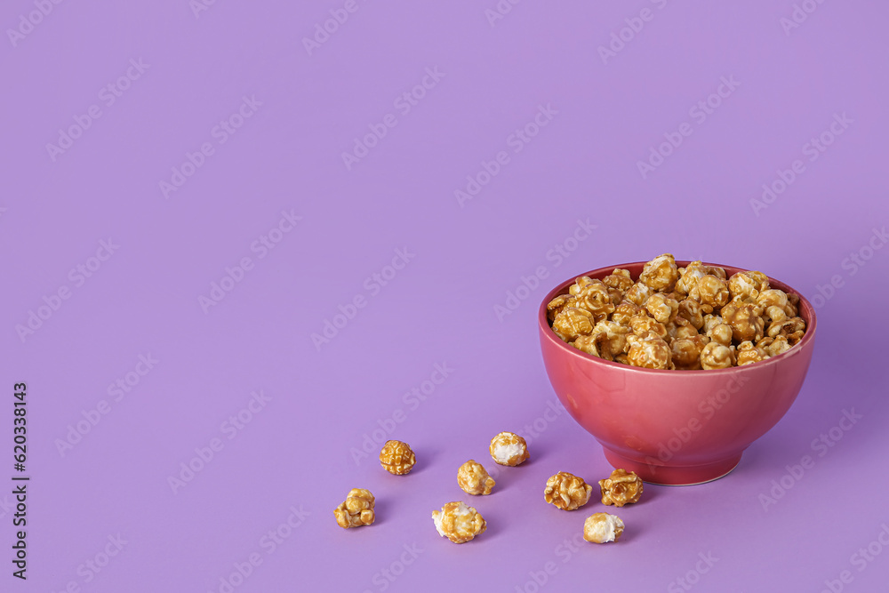 Bowl with tasty popcorn on purple background