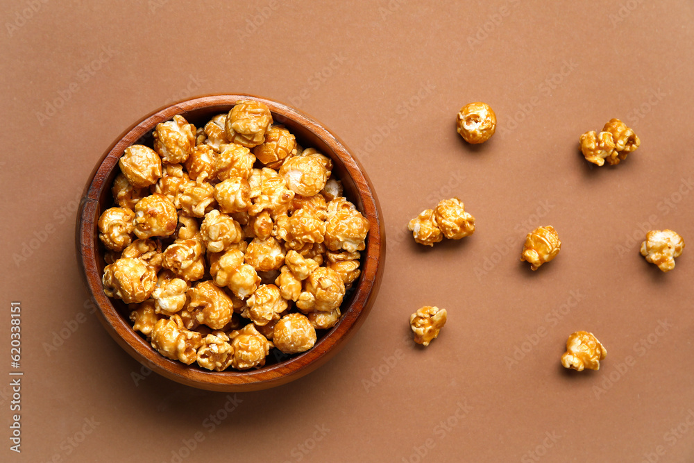 Bowl with tasty popcorn on brown background