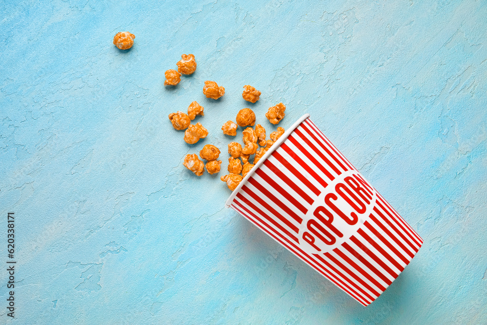 Bucket with tasty popcorn on blue background