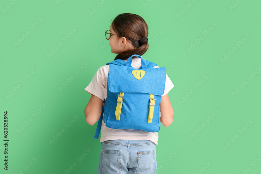 Little girl with backpack on green background, back view