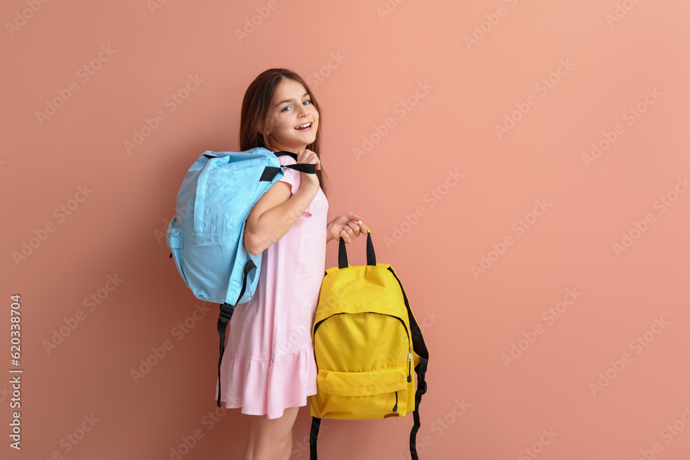 Little girl with backpacks on pink background