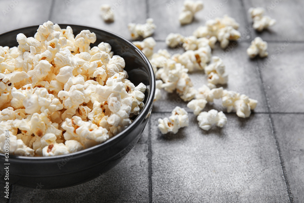 Bowl with tasty popcorn on grey tile background