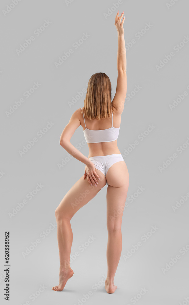 Young woman with cellulite problem on light background, back view