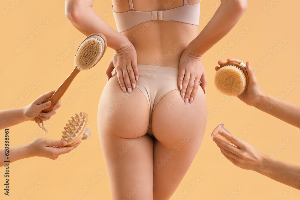 Young woman and female hands with anti-cellulite brushes on beige background