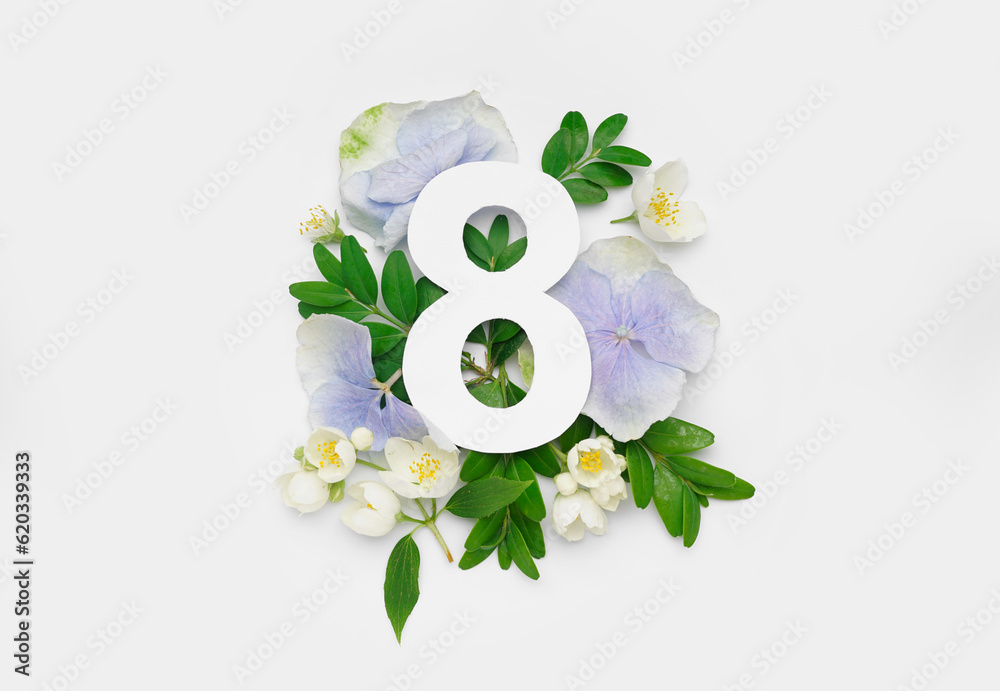 Green leaves and flowers with paper number eight on white background