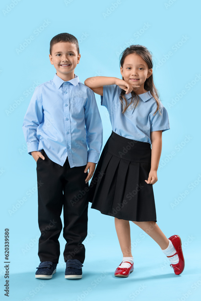 Little schoolchildren on light blue background